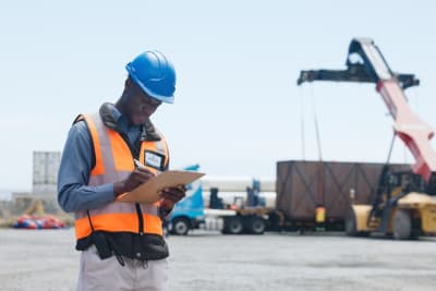 Man working in a port with a shipping container at the back