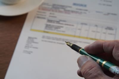 Person holding a pen and a document is in the background