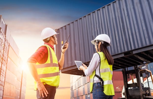 Two people in a port watching a container