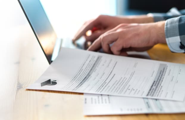 Person typing on a laptop and with documents