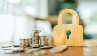 Pile of coins on a table next to a locket made of wood