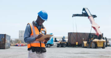 Man working in a port with a shipping container at the back