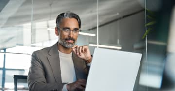 Man wiyh glassed looking at a laptop