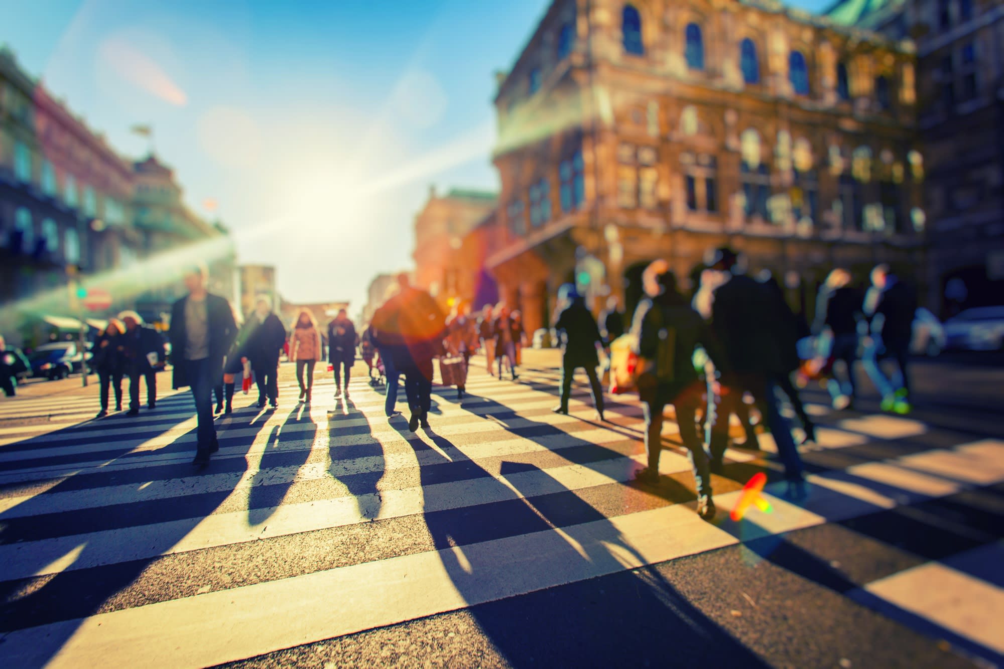 A diverse group of people walking on a busy zebra crossing in an urban area