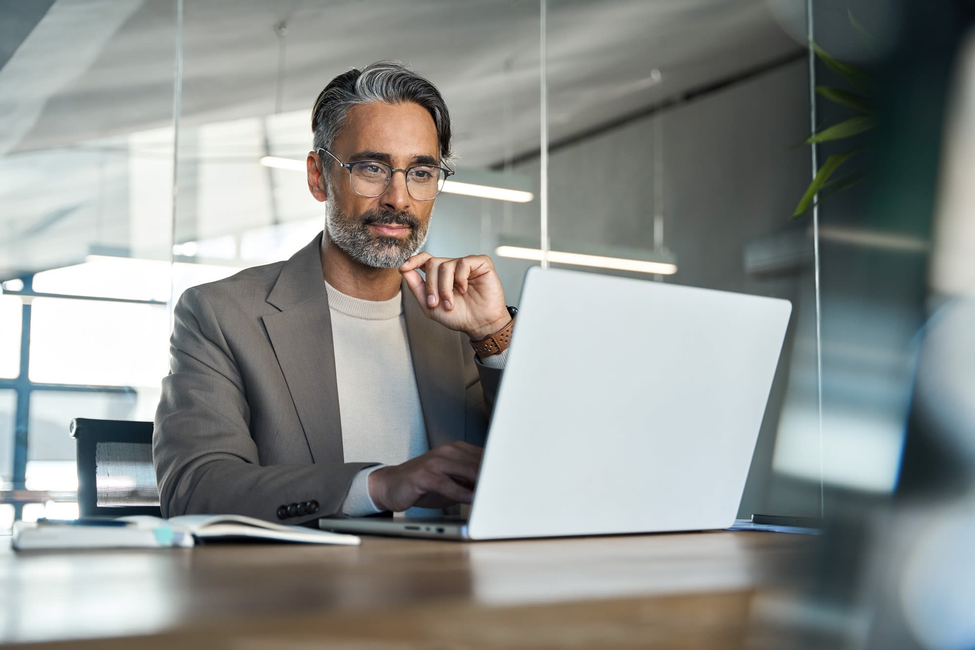 Man wiyh glassed looking at a laptop