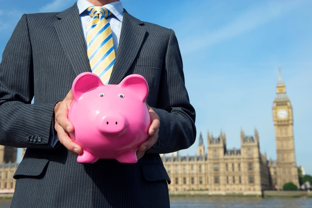 man holding a piggy with the Parliament in the background.