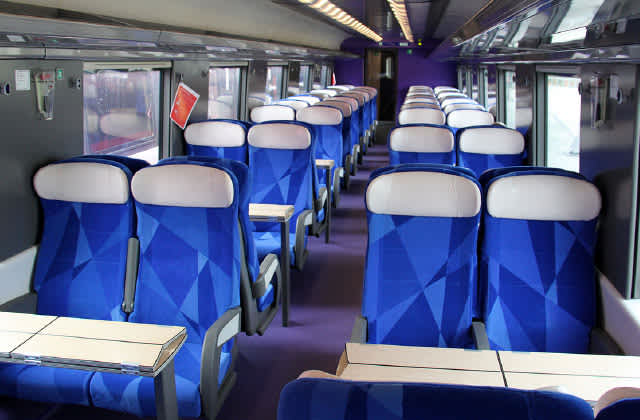 Train passenger car interior showing seats, tables, walls and more
