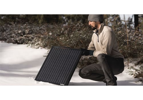 Person setting up a Furrion solar panel in the snow