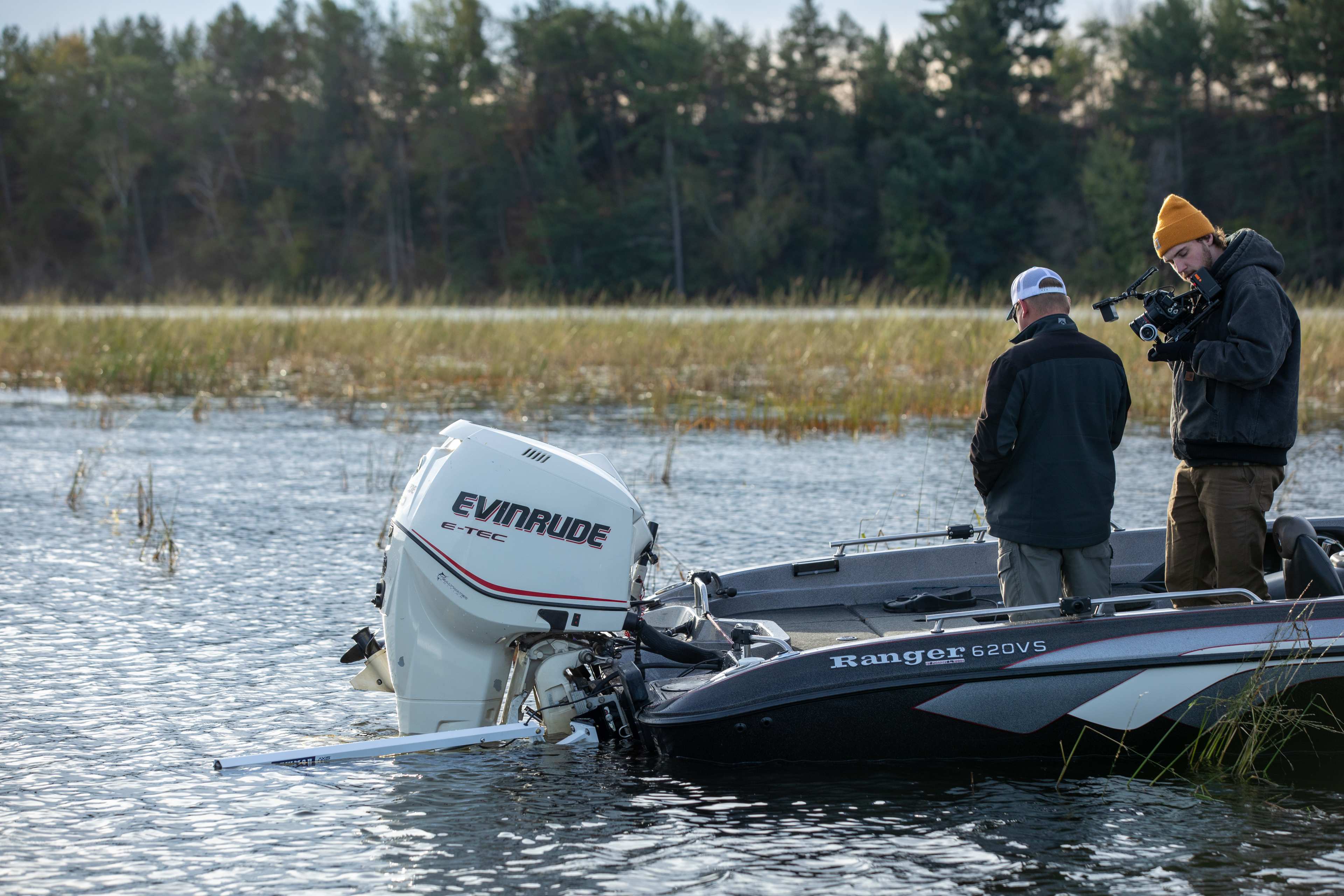 Bass boat anchored on a calm freshwater lake with Lewmar Axis electric anchor pole deployed vertically from the transom