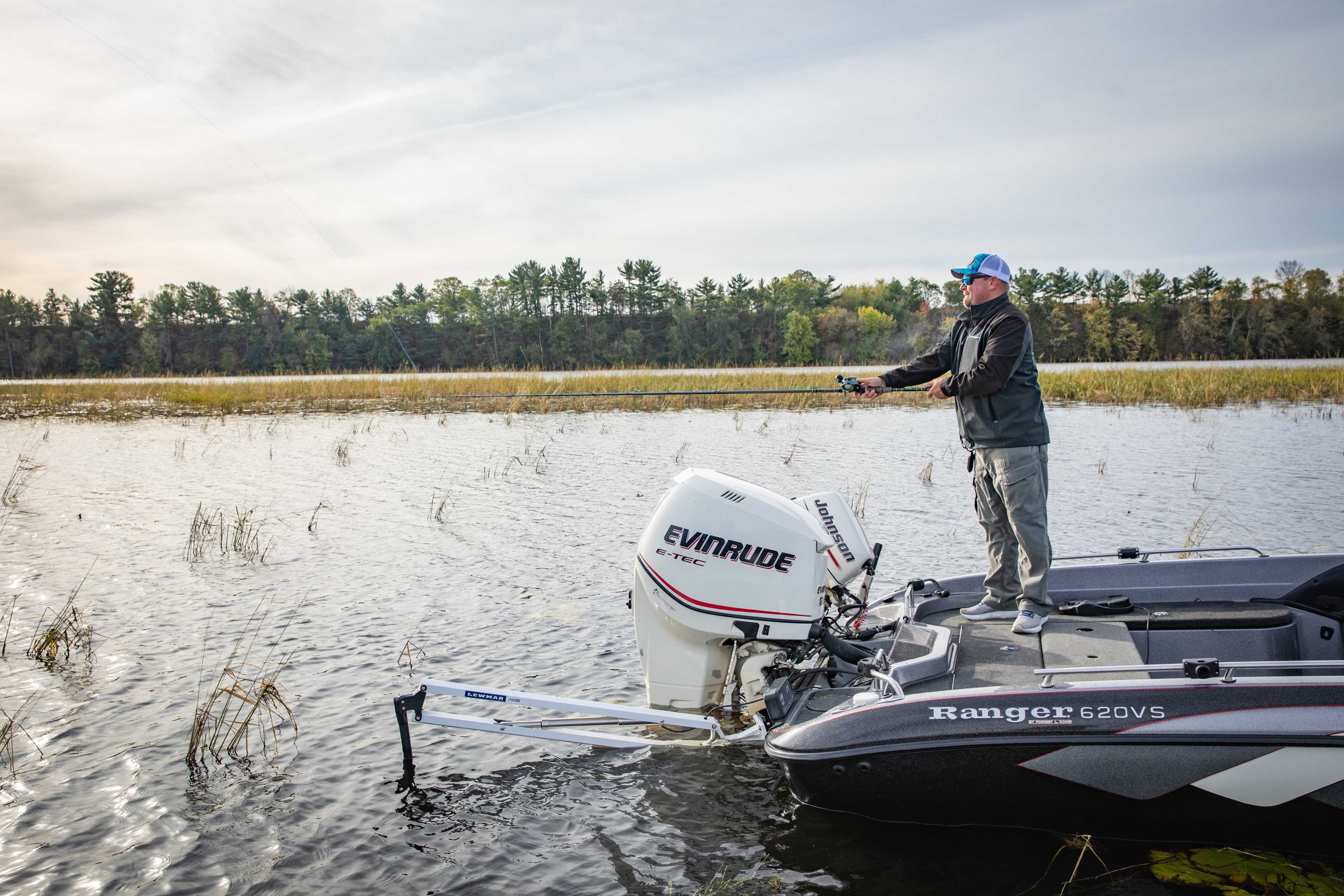 Angler casting from the bow of a bass boat while Lewmar Axis anchor holds position on a submerged point in freshwater lake
