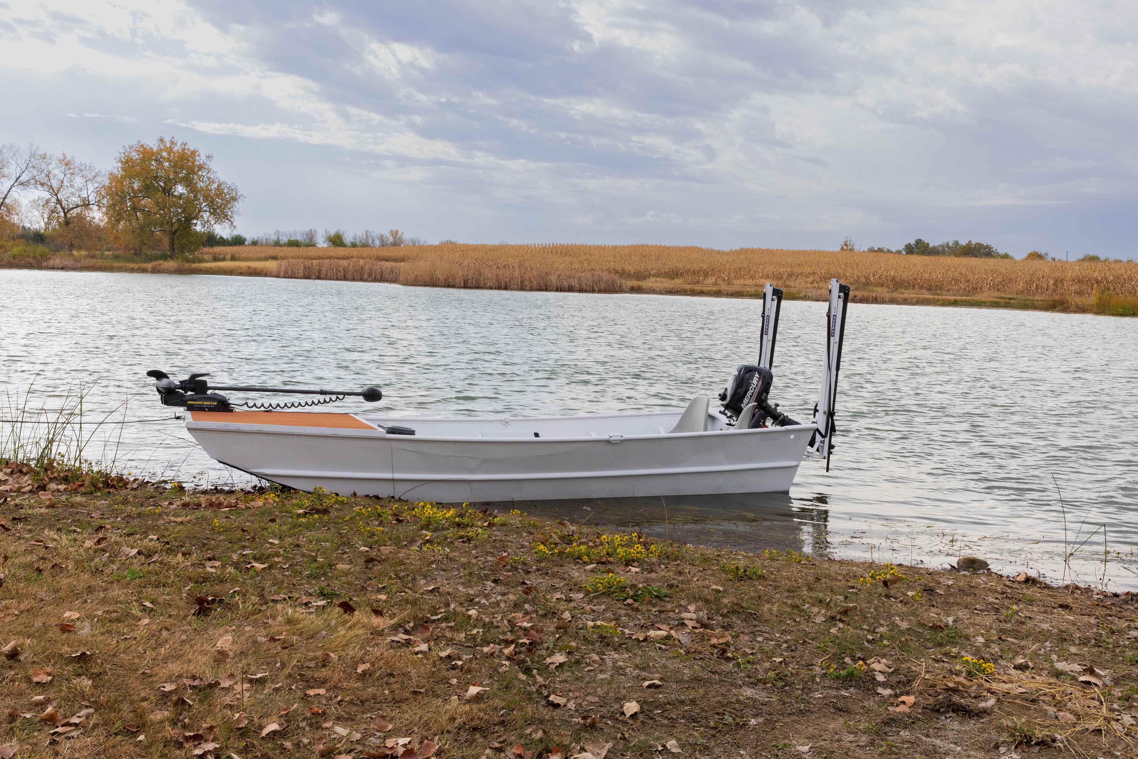 White jon boat on a lake with two white Lewmar shallow water anchors stowed upright at the transom