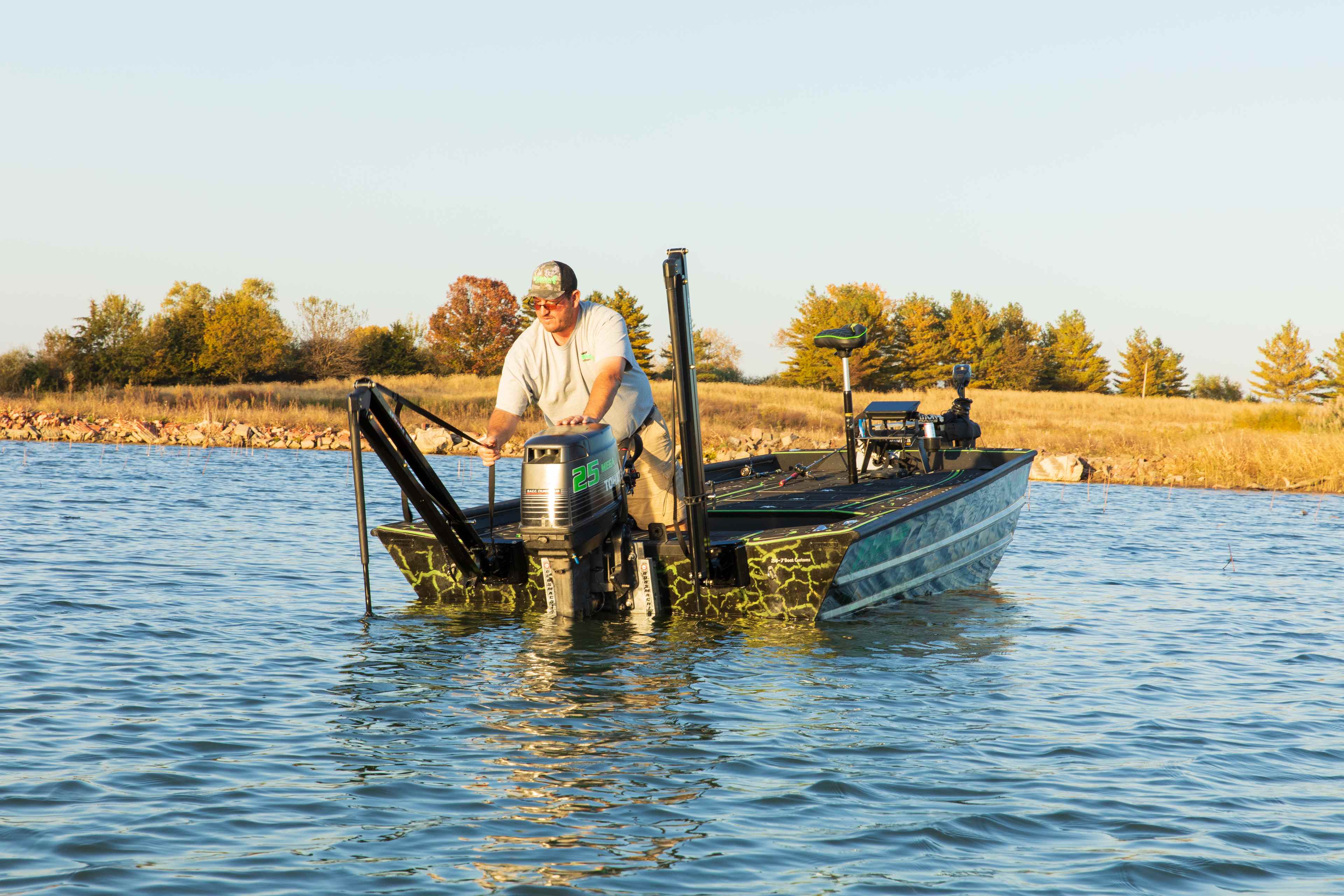 Angler at the transom of a bass boat with a shallow water anchor in the water and a trolling motor stowed on the bow
