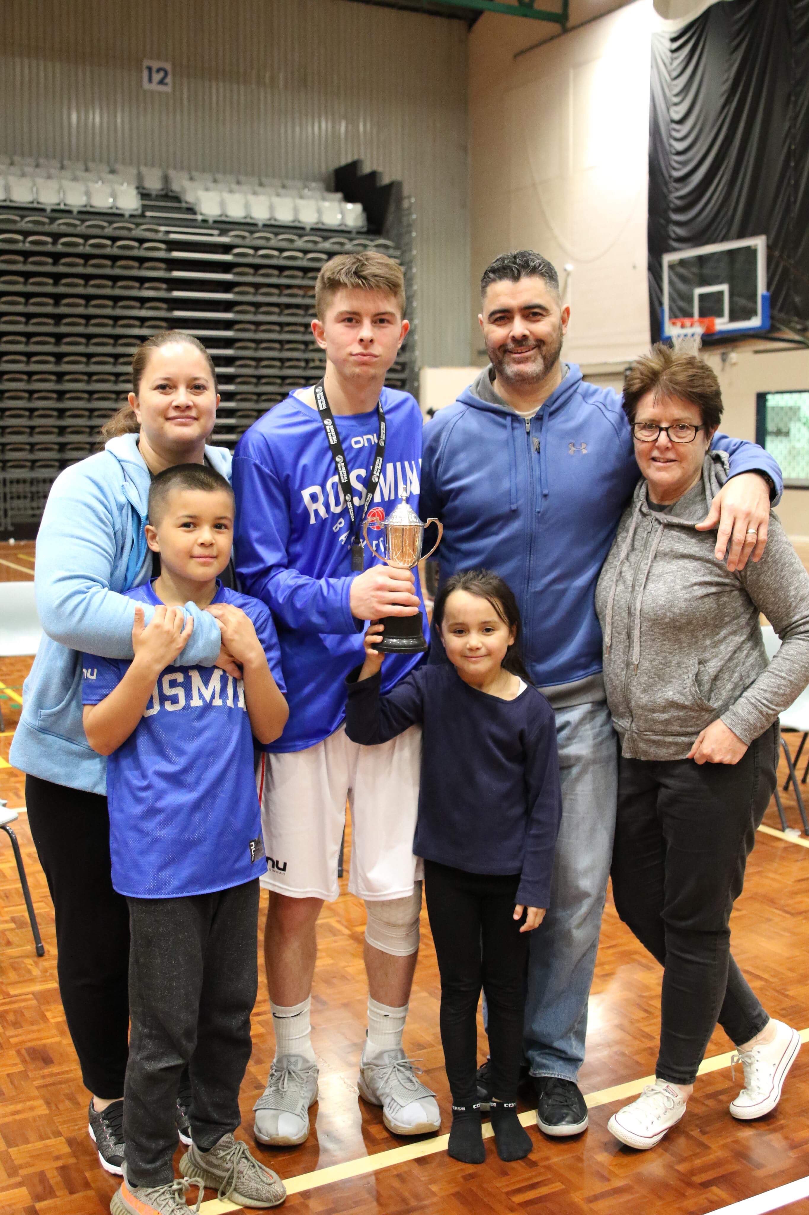 Kainoa with his family, holding a trophy