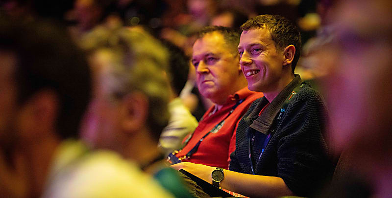 Close up of two audience members smiling as they listen to a talk