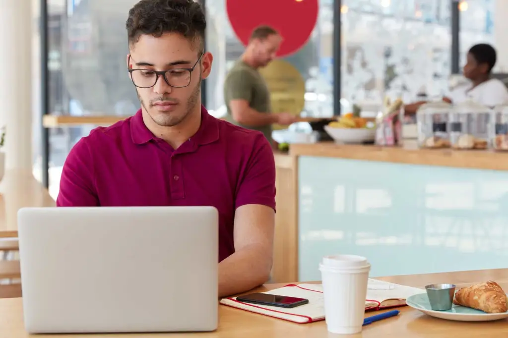 Person writing content on laptop in coffee shop