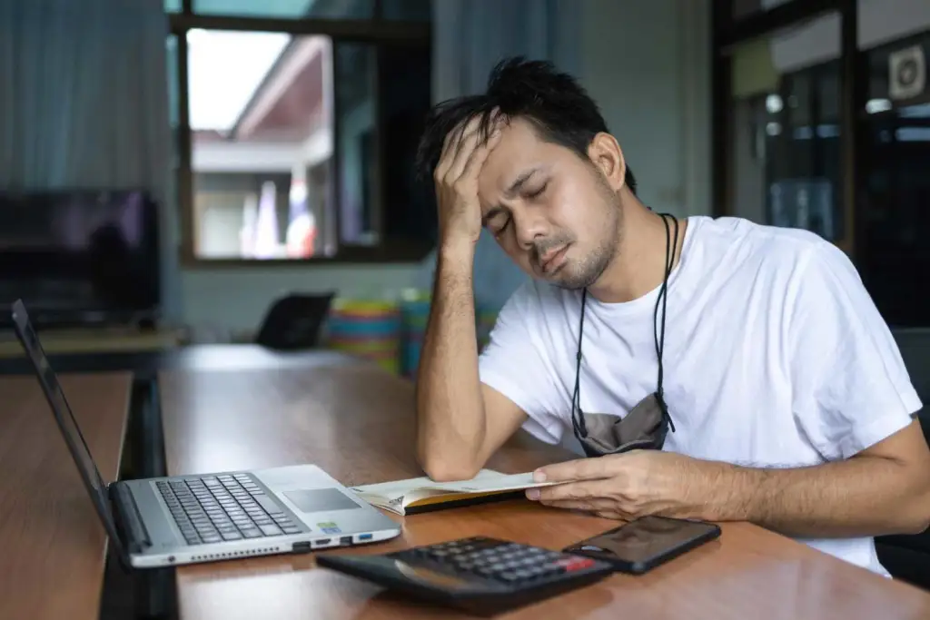 Student looking stressed at finances while coding