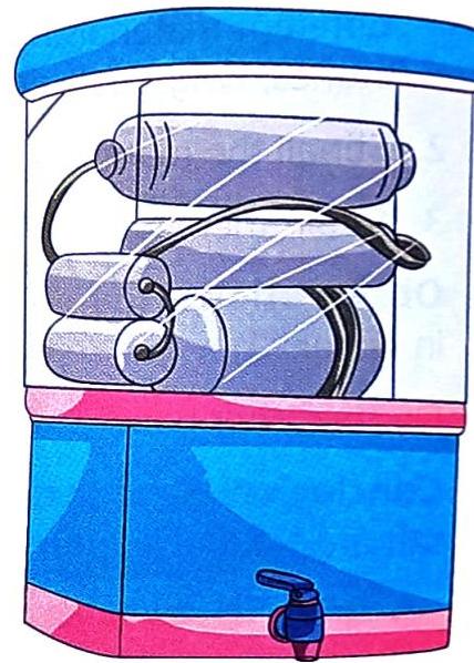 A transparent water purifier has a blue curved top and a blue base with pink trim. Inside the transparent casing, several cylindrical filters, colored light purple with dark stripes, are arranged and connected by black hoses. A blue tap with a silver handle is located on the front of the base.