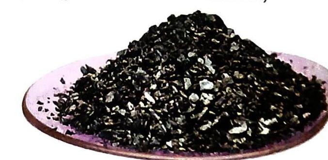 A pile of dark, irregular fragments rests on a pinkish-brown dish.
