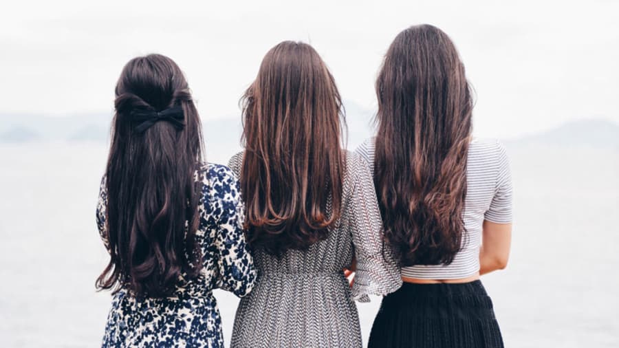 Three women with long hair standing next to each other