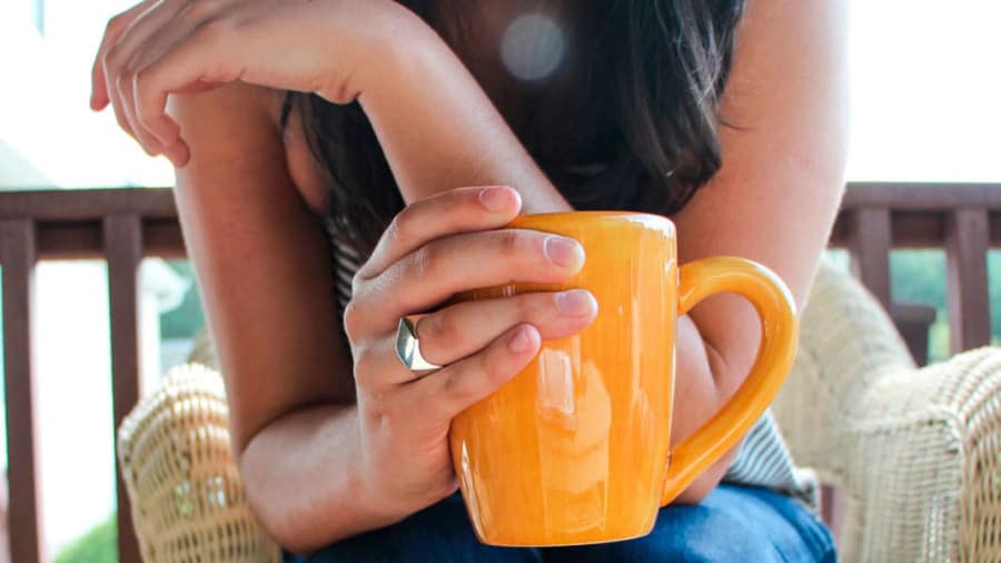 Woman holding orange mug sitting on a straw chair without psoriasis