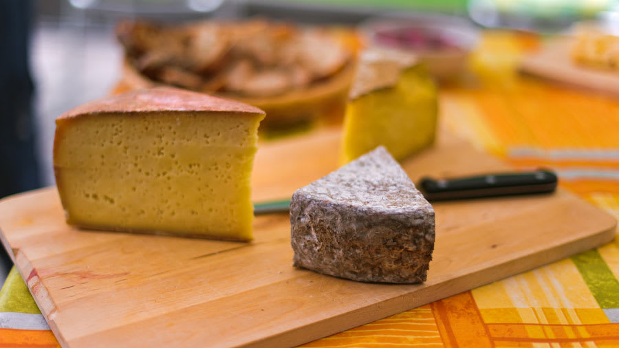Assorted cheeses and and knife on a wooden cutting board