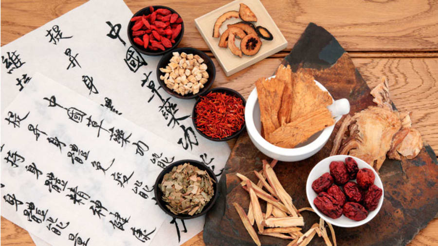 Chinese herbs on wooden table next to Chinese writing