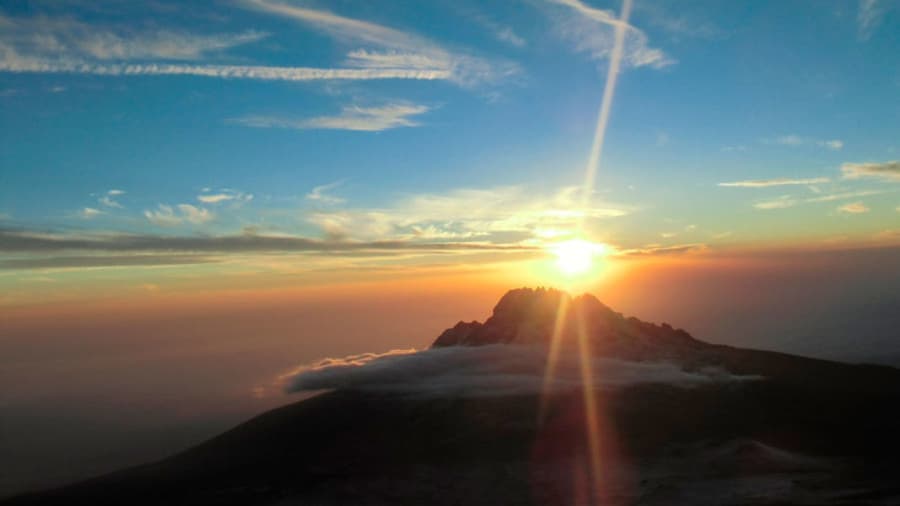 Sunrise over the horizon above mountains and clouds