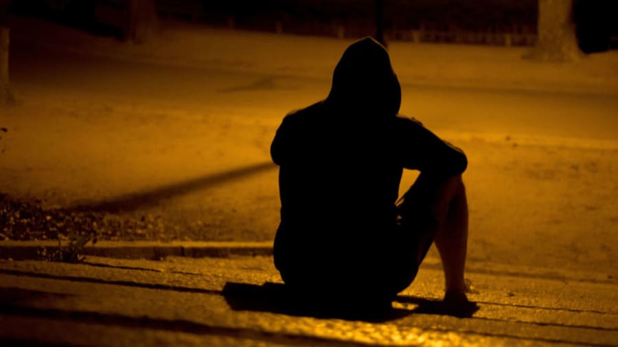 Depressed person sitting in the shadows at night