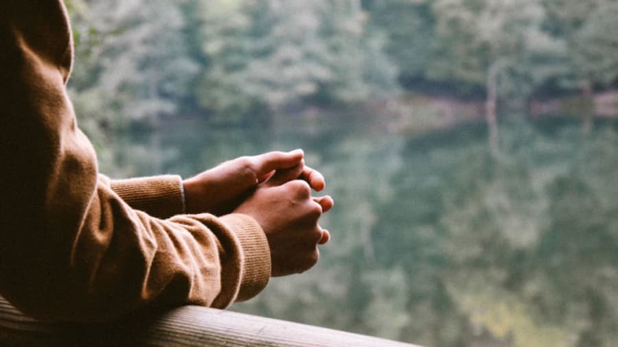 Arms folded on wooden rail overlooking trees