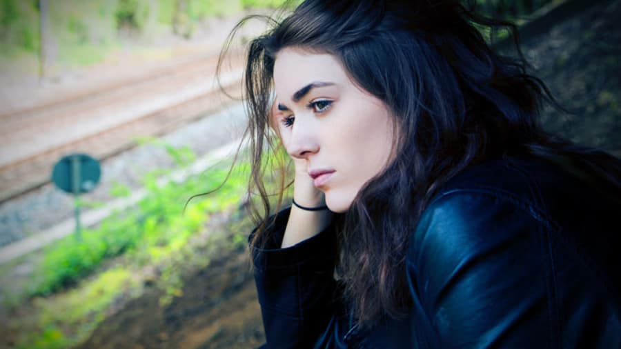 pretty girl with black hair dressed in black looking sad and thinking to herself