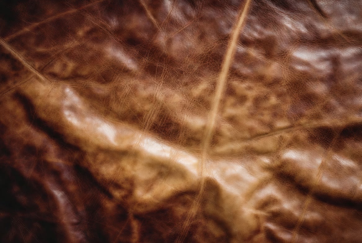 Distressed leather pull-up effect Close-up of brown distressed leather showing the pull-up effect, with lighter tones where oils and waxes shift under stress
