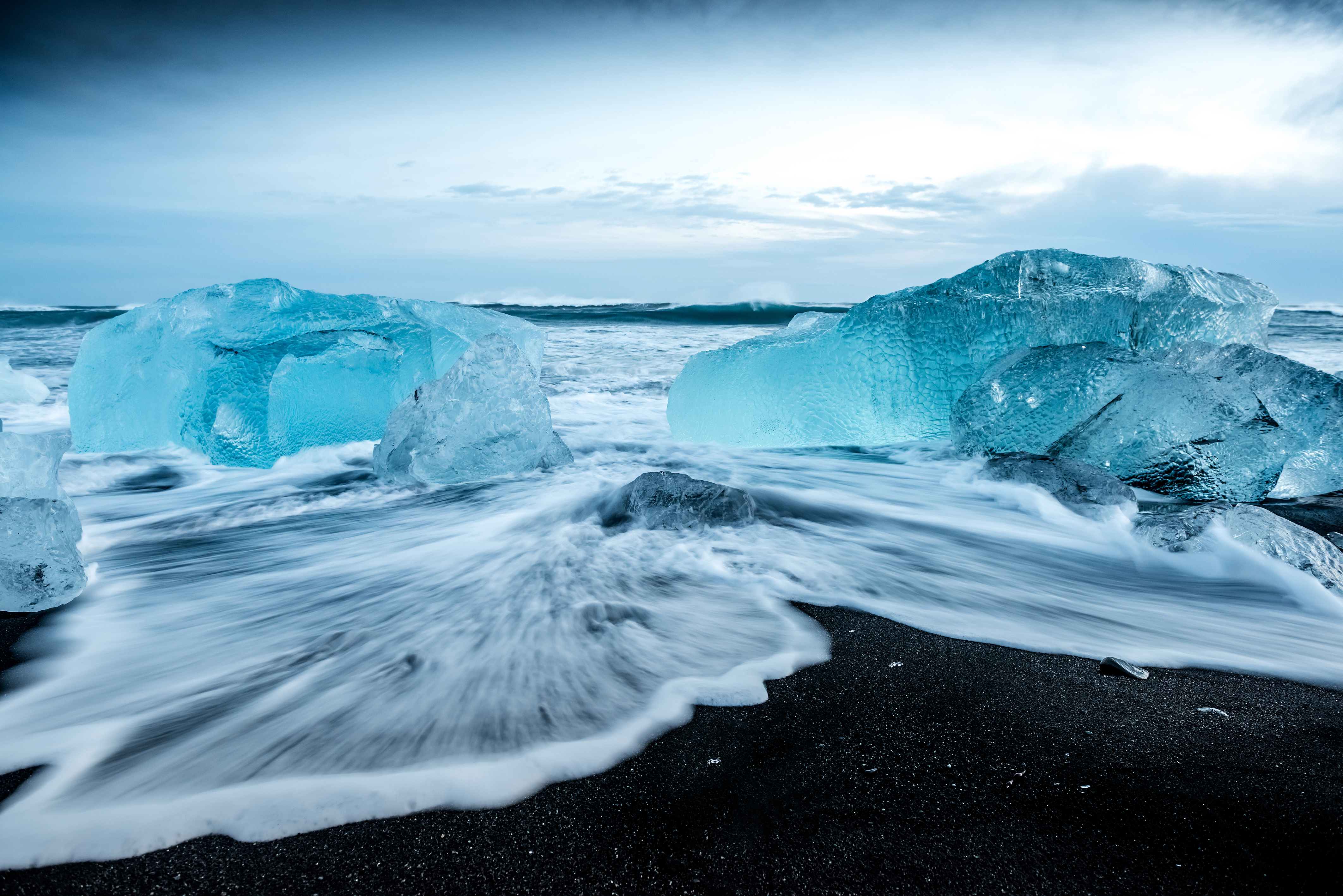 Crystal Beach in Iceland, overlooking the sea with two large icebergs.