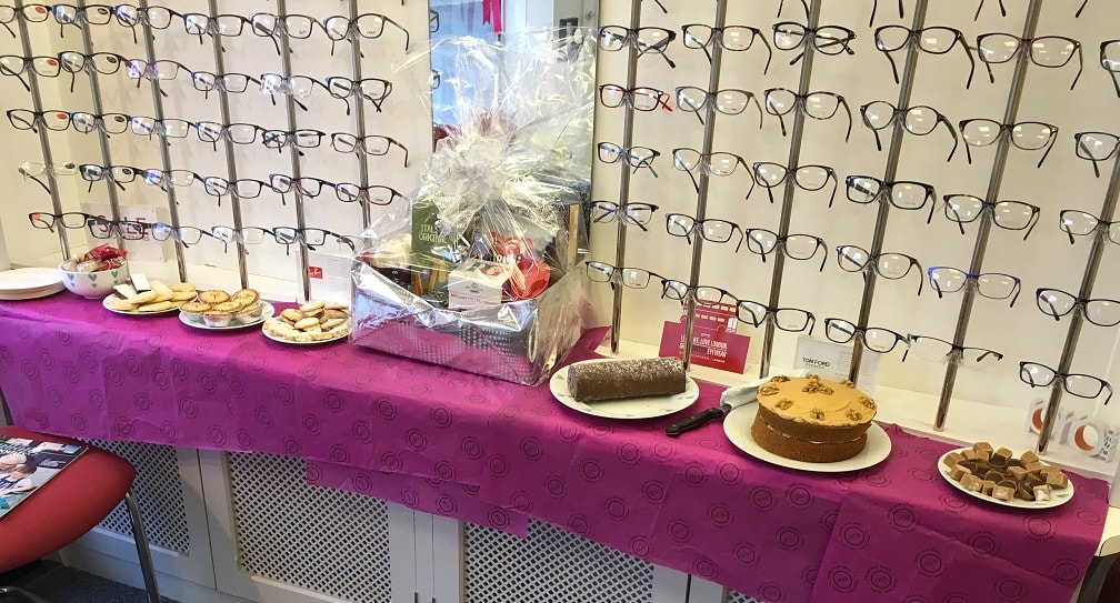 Table with a hamper basket, some cakes and biscuits.