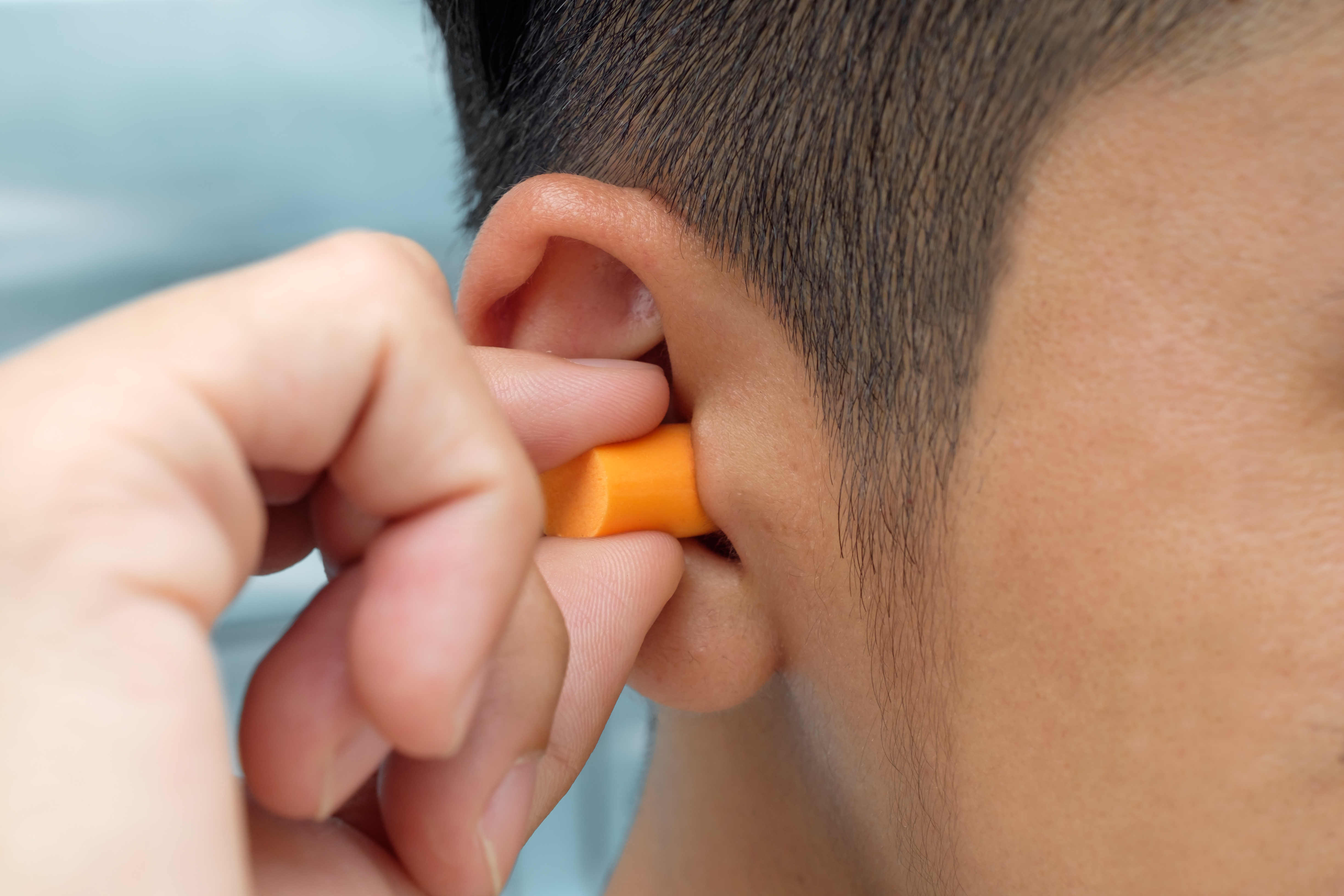 A man putting on general ear plugs.