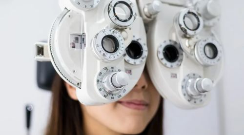 Woman having Leightons eye test with phoropter head technology.