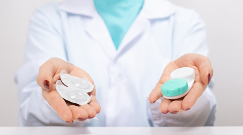Optometrist holding one-day contact lenses and reusable contact lenses in their hands, illustrating the options available for vision correction.