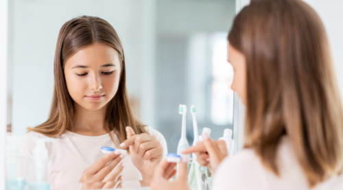 A young teenager in her bathroom preparing to put in her contact lenses.