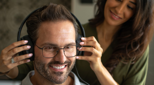 Audiologist placing headphones on a patient's head in preparation for a hearing test.