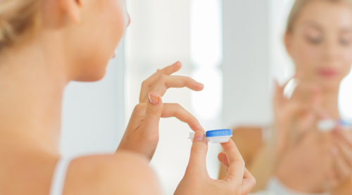 A woman in her bathroom preparing to put on her contact lenses.