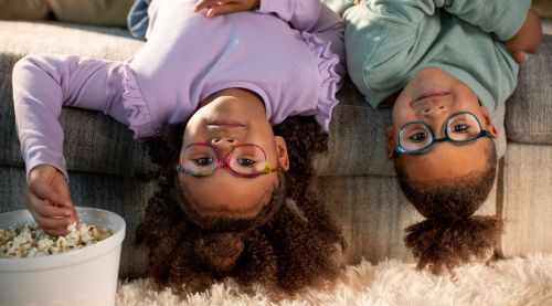 A brother and a sister sitting upside down on sofa.