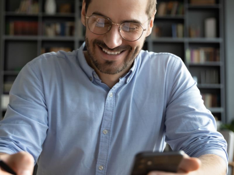 A man, wearing eyewear, smiling while writing down