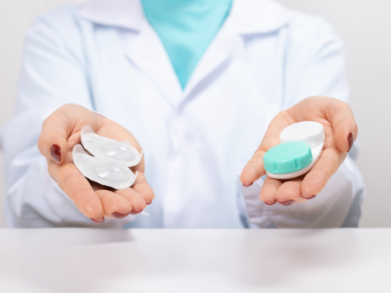 Optometrist holding one-day contact lenses and reusable contact lenses in their hands, illustrating the options available for vision correction.