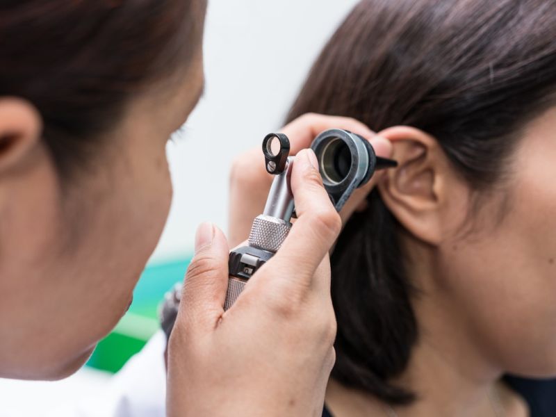 Man inspecting inside of woman's ear