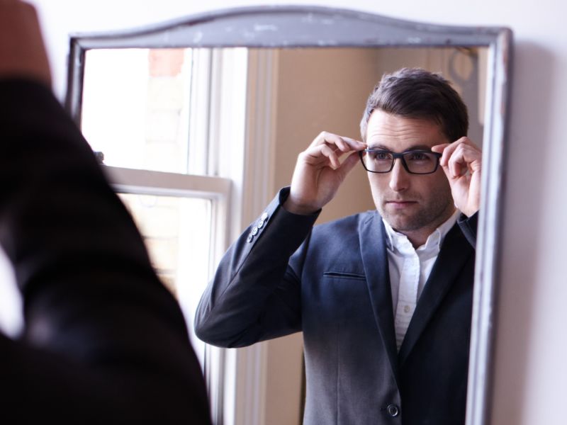 Man checking out glasses in mirror