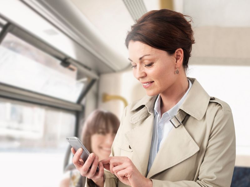 Woman on bus looking at smartphone and smiling