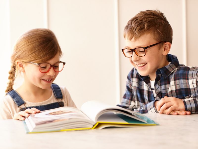 Children wearing glasses and reading book