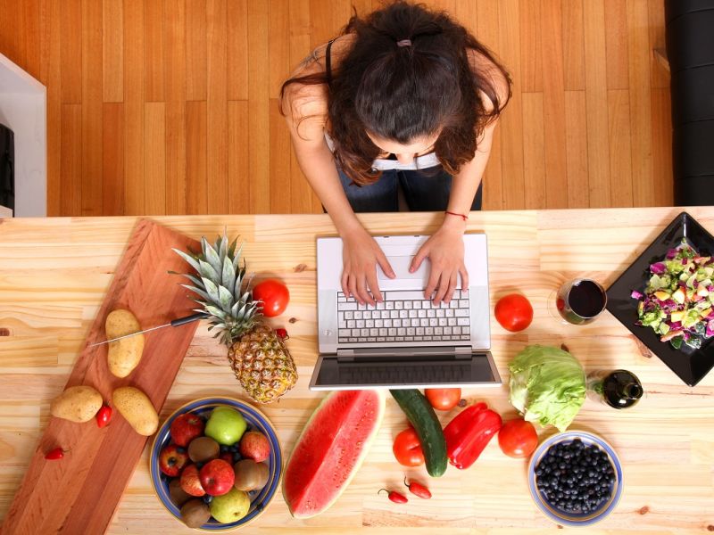 Woman at desk on laptop with fruit and vegetables