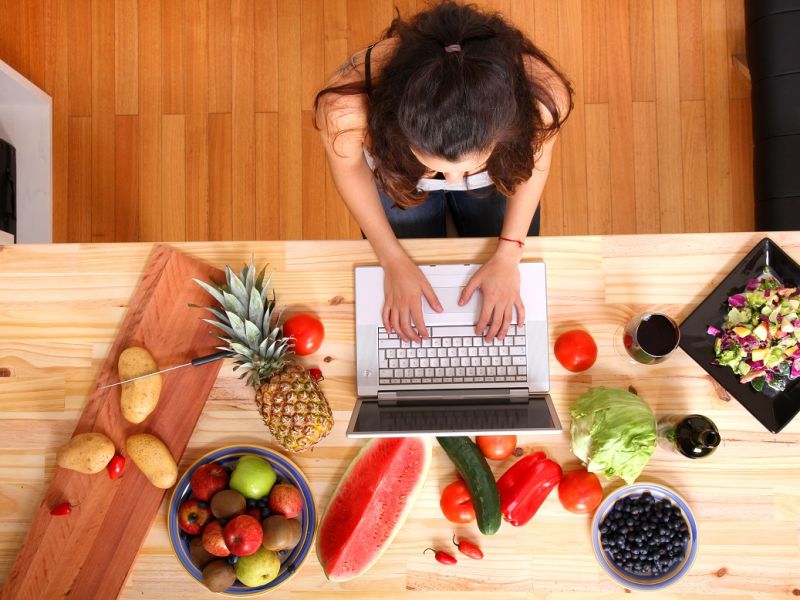 Woman at desk on laptop with fruit and vegetables