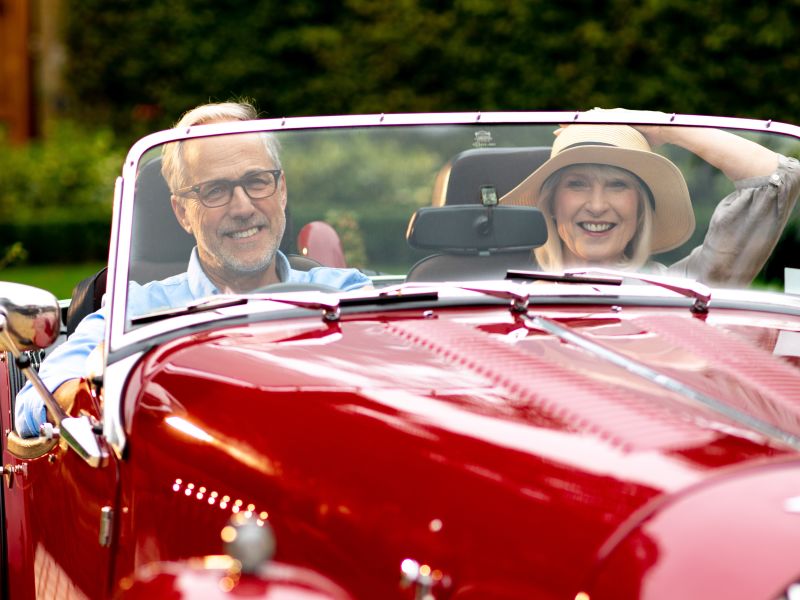 A smiling couple in a red car.