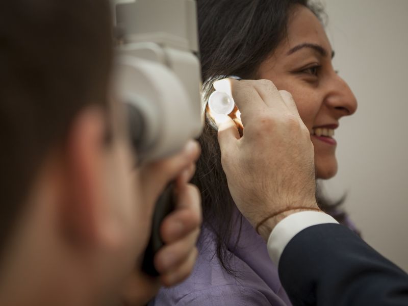 Man inspecting inside of woman's ear